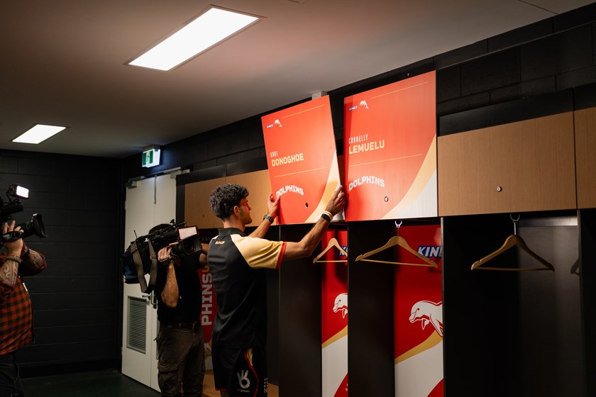 Dolphins staff adding signage to Suncorp Stadium dressing sheds.